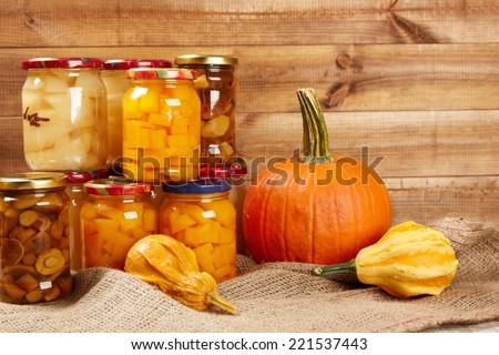 Preserved autumn vegetables on shelf in wooden wall