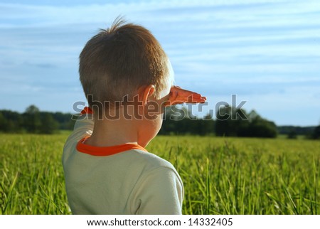 happy young boy looking horizon and dreaming on green field grass