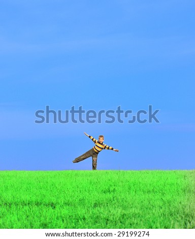 Young boy with his arms wide open on grass