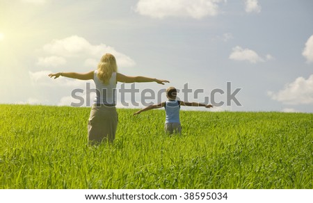ma and son walk in field. agricultural nature landscape with blue cloud sky and green grass