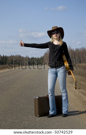 country woman with guitar on the road in auto-stop