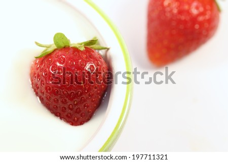 fresh ripe strawberry in a white bowl with white yogurt on white background