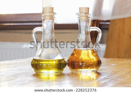 transparent glass bottles of olive oil and vinegar on a wooden table