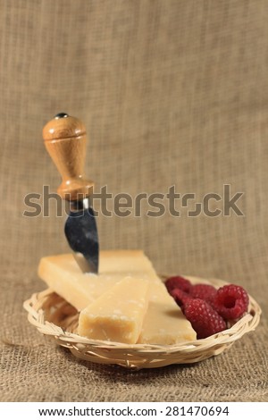 Parmesan cheese and slice in a basket, special little knife for parmesan,on natural jute tablecloth