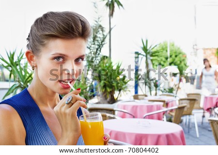 Closeup of a cute young lady drinking orange juice at a restaurant  - Outdoor