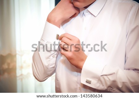 hands of the groom of a cuff link