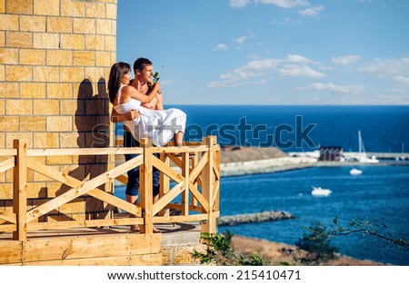 Couple posing on a balcony with sea in the background