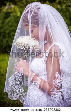 Young attractive bride sitting with bouquet of flowers smiling