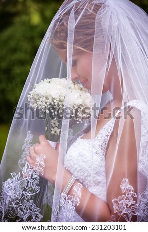 Young attractive bride sitting with bouquet of flowers smiling
