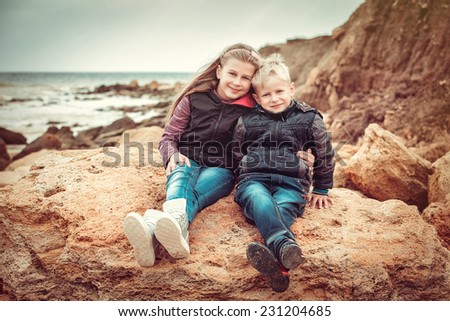 Smiling happy brother and sister posing on a beach