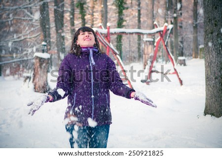 Happy girl playing with snow in the winter landscape