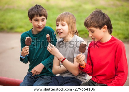 Happy smiling boys eat ice cream on park