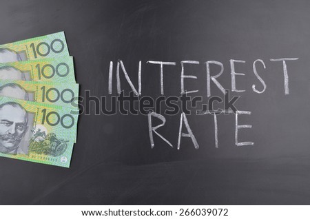 One hundred Australian dollar bills on a blackboard where interest rate is written in chalk