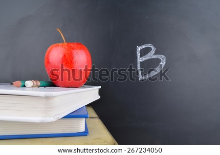 Classroom with red apple, books and blackboard with school grade