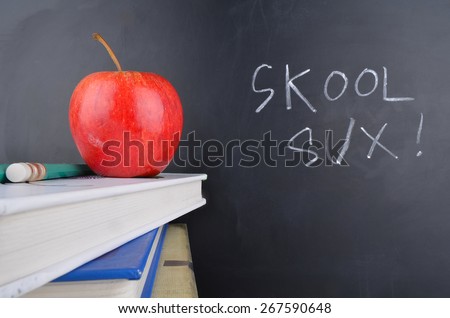 Classroom with red apple,books and handwriting in white chalk on blackboard