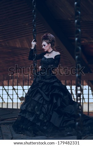 Mysterious woman dressed in gothic dress posing in ruined building