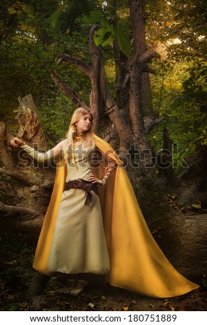 Blond girl dressed in dress walk in a magic forest