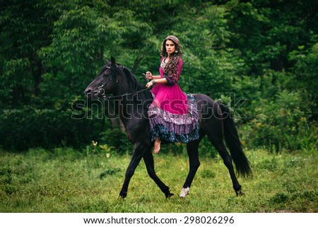 Beautiful woman on a horse dressed in long violet dress
