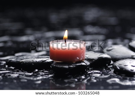 tranquil spa scene - burning spa candle with zen stones with water drops
