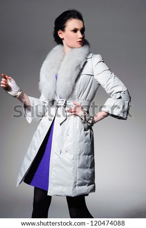 Stylish model in fur coat in white coat posing