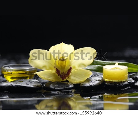 Yellow orchid and black stones and candle on black ground