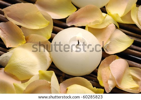White candle and rose petals on mat