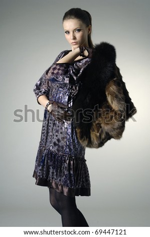 High fashion model in winter fur coat clothes posing in the studio