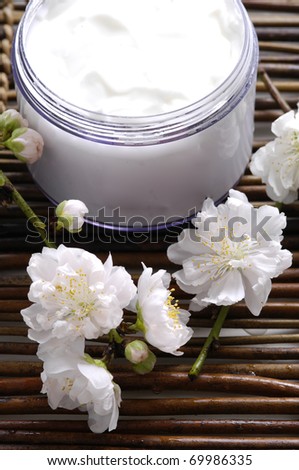 Skin cream and beautiful spring white flower on mat