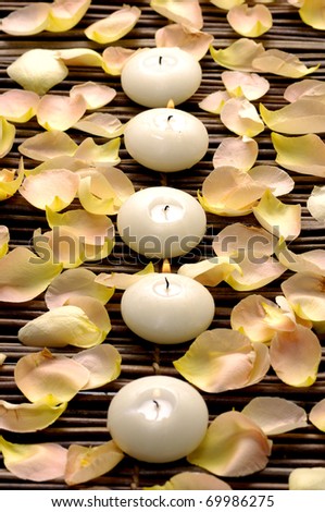 A line of white candle and rose petals on mat
