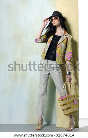 High fashion model wearing sunglasses with bag posing in the studio