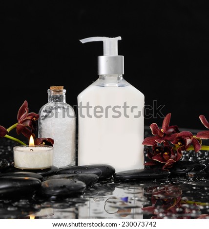 Red orchid with massage oil ,candle, salt in glass on zen stones