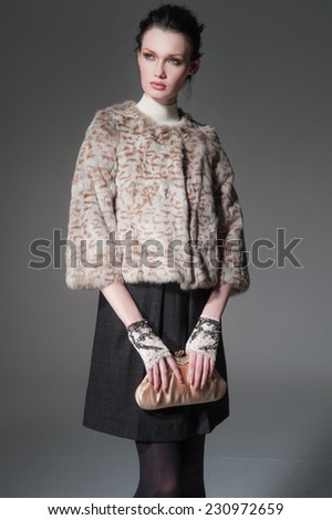 portrait of fashion model holding little purse posing on light background