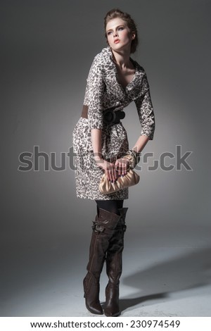 Full body Studio portrait of a young woman with a purse posing on light background