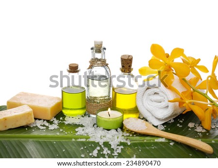 spa supplies with orchid, oil, yellow candle ,soap ,salt ,towel on banana leaf