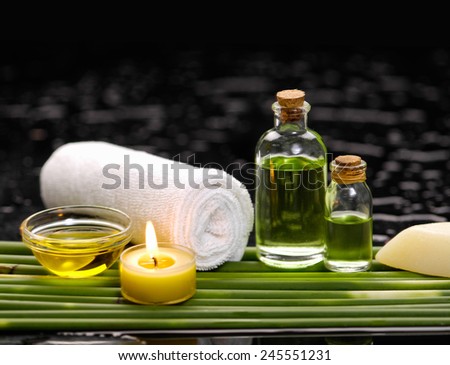 Still life with massage oil and candle, with row of plant stem