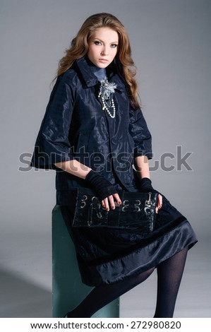 Full body fashion model in fashion dress holding purse sitting cube
