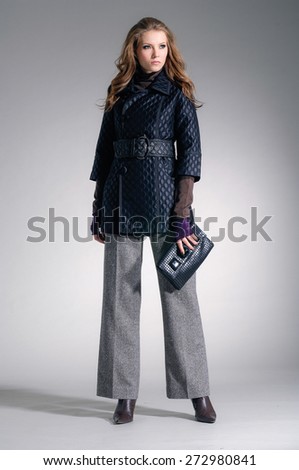 full-length,fashion model clothes holding handbag posing-gray background