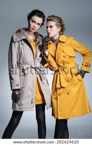 fashion two model in coat clothes posing on light background