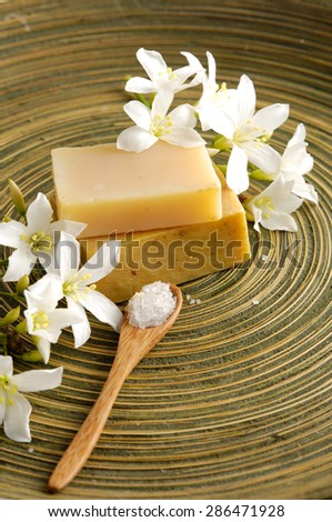 gardenia flower with soap, salt in spoon in wooden bowl