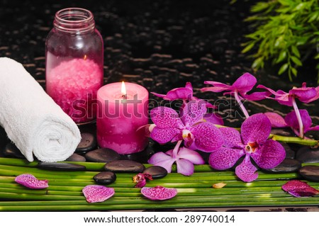 Still life with pink orchid and candle, oil, towel with row of plant stem