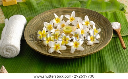 Many white flower with soap, salt in spoon in wooden bowl ,towel on banana leaf