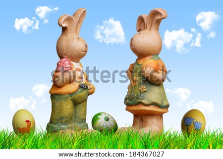 two easter bunny dolls, arranged with grass sky, clouds, eggs and crocuses