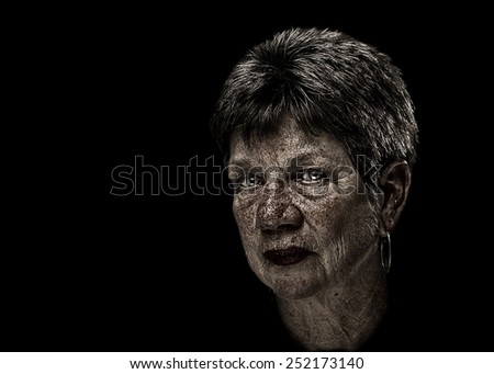 Senior elderly older wise woman portrait with short hair and desaturated with wrinkles sunspots and serious judgmental melancholy sad depressed disappointed expression isolated on black background