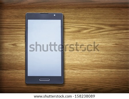Black smart phone on wooden desk.