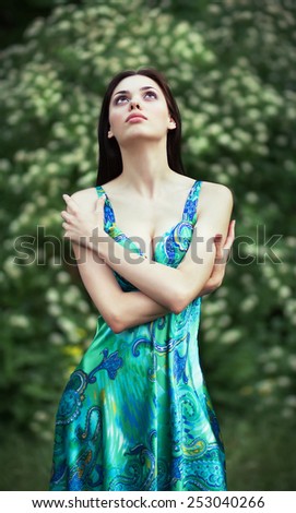 Sensual young woman, smiles sweetly in the flowered garden, day dreaming