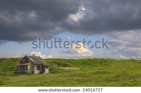 Deserted house on a empty green field. On a clouds background.