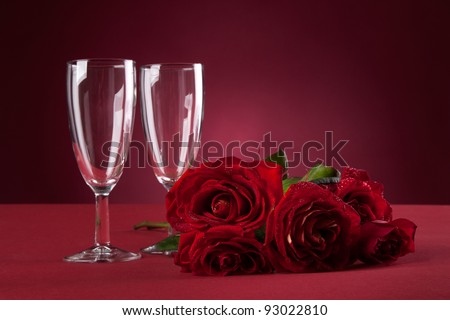 bouquet of red roses and two glasses on a red background