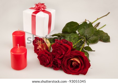 red roses, two candles and white gift on a white background