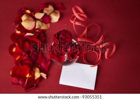 bouquet of red roses with white cards and rose petals on a red background