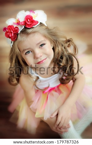 Beautiful little girl sitting on the floor in a tu-tu and looking up